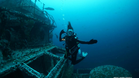 Scuba diver poses with sunken ship