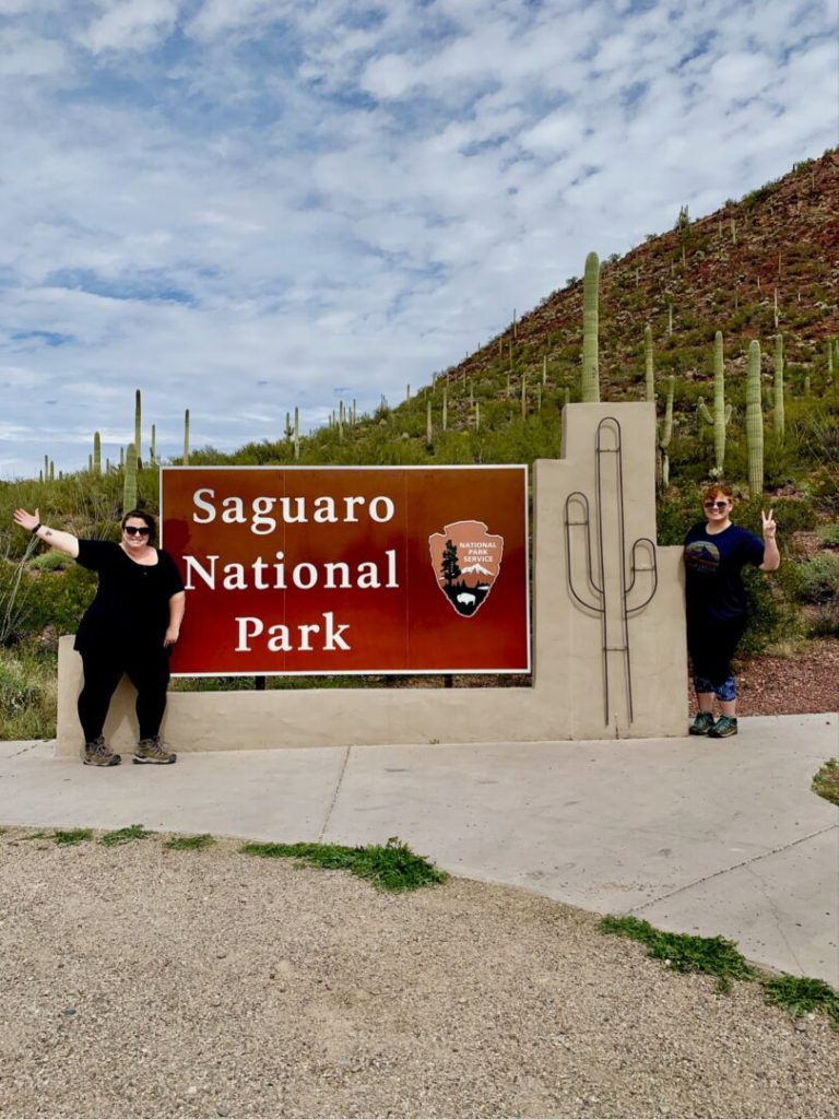 Couple poses in front of Saguaro National Park sign