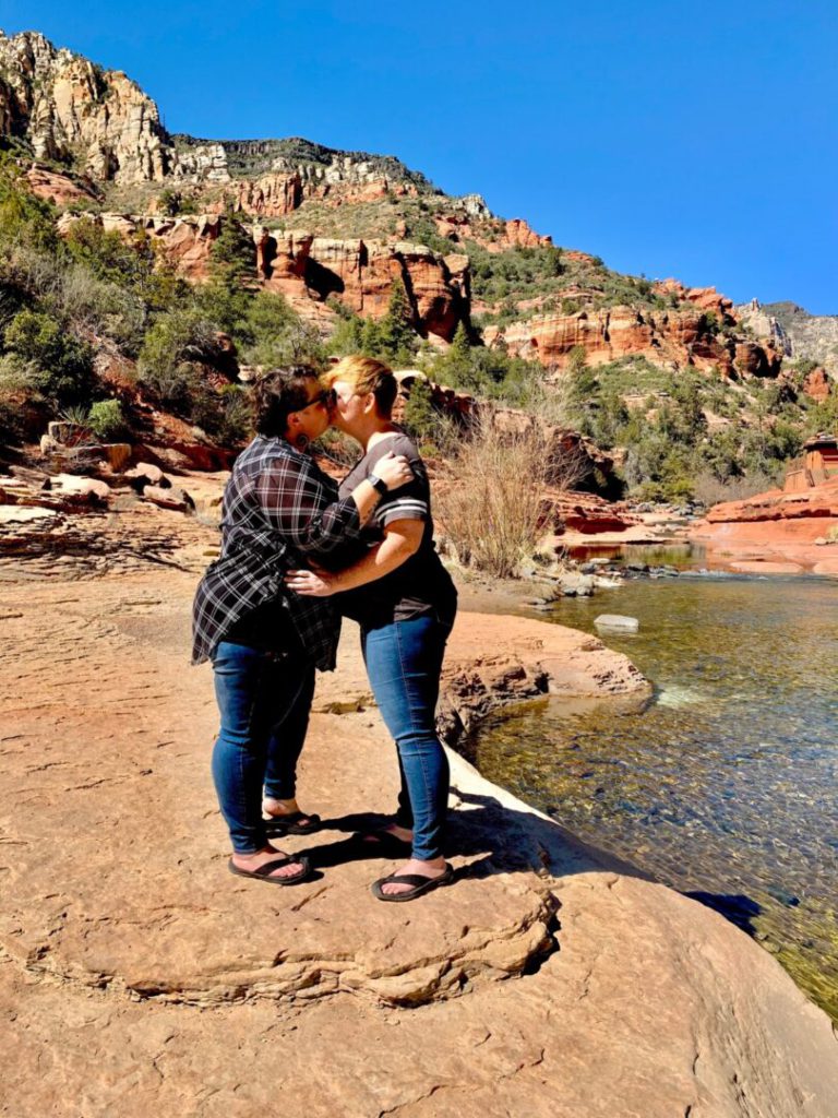Couple kisses along a river on hike in Arizona