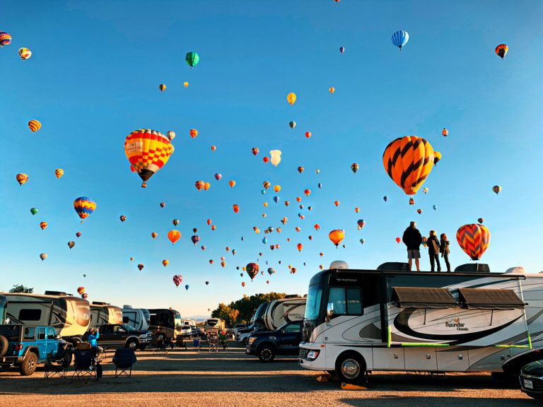 hot air balloons soar above RVs