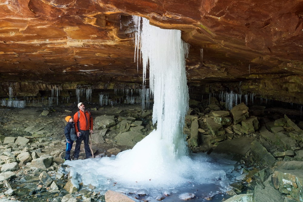 Father and son looking at the frozen waterfall Glory Hole Falls. Arkansas, United States