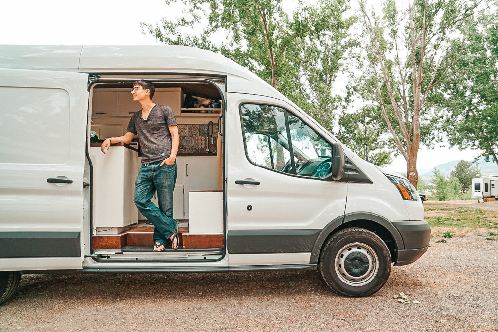 man stands in the open door of his camper van