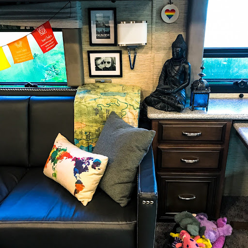 Decorated living room couch of an RV with colorful pillow of a world map and basket of dog toys
