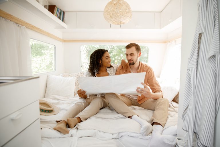 Couple looks at a map sitting in the bed of their RV