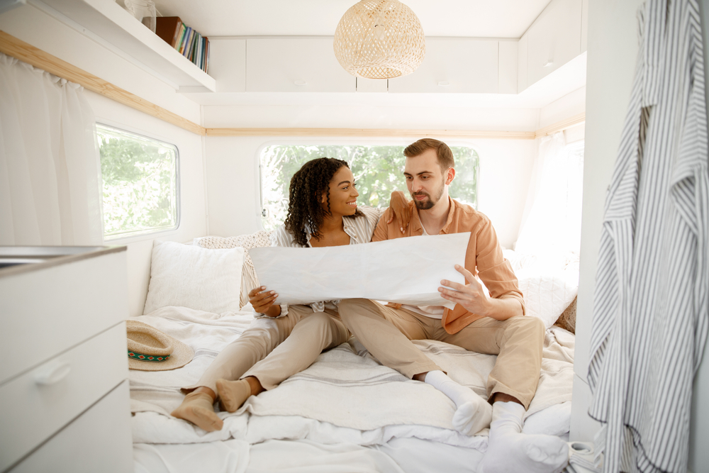 Couple looks at a map sitting in the bed of their RV