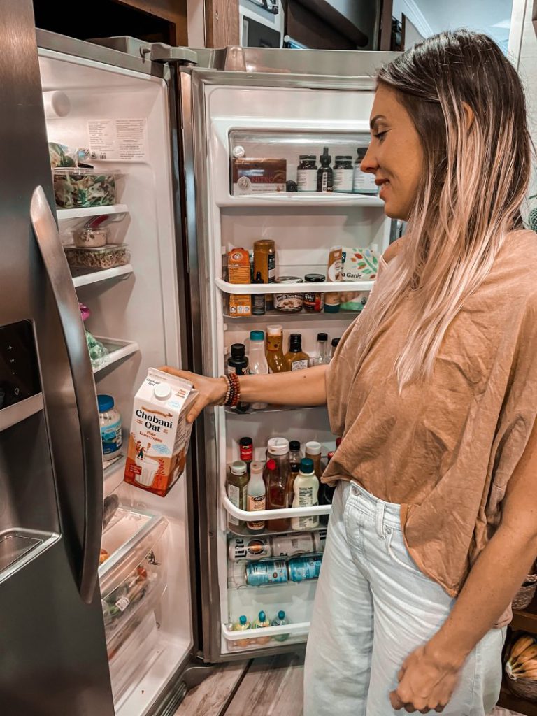 Woman puts oat milk back into fully stocked fridge