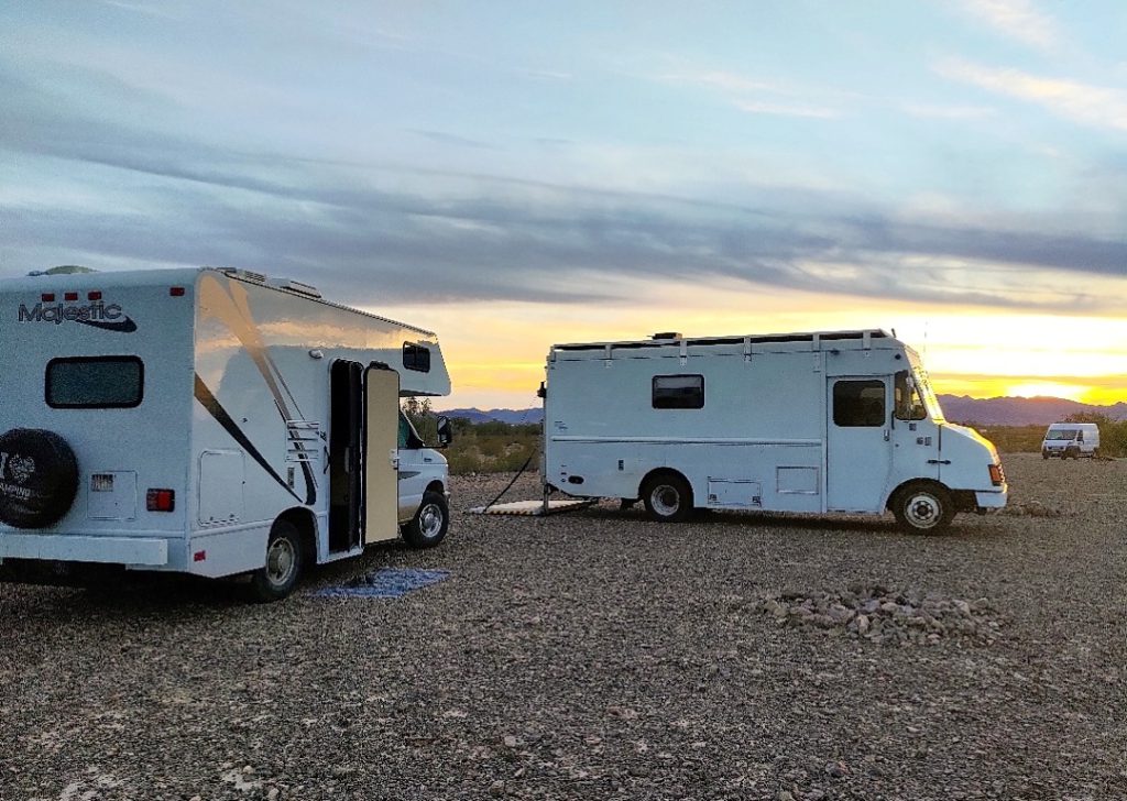 Two class c rvs parked by each other at sunset