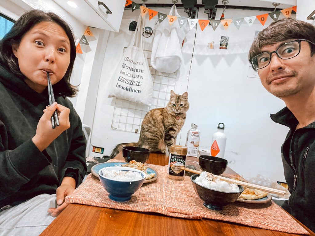 Couple eating dinner with their cat in an RV