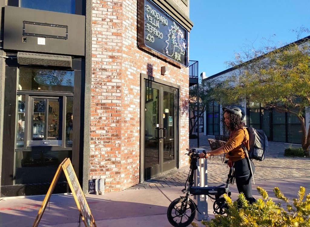 woman with her bike in front of a coffee shop