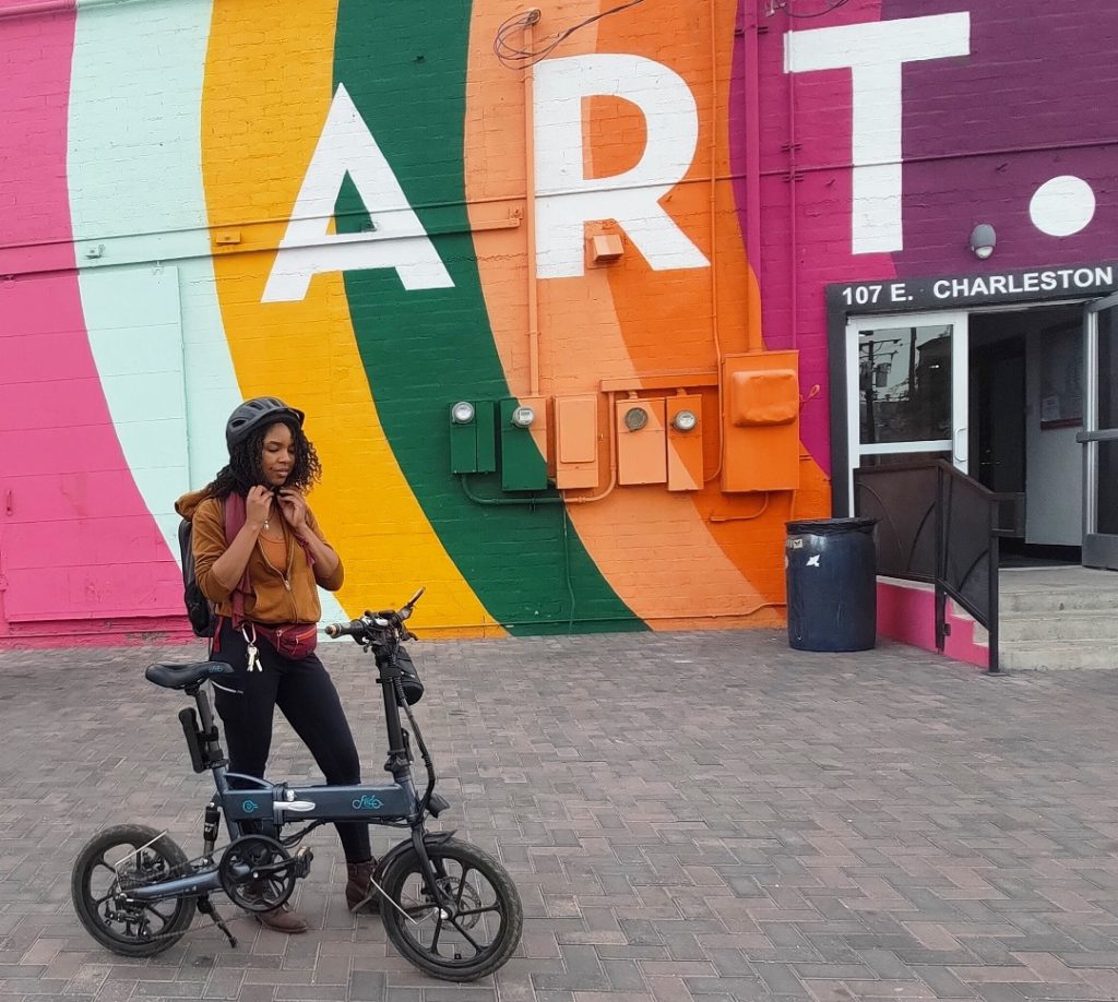woman with her bike in front of an art mural