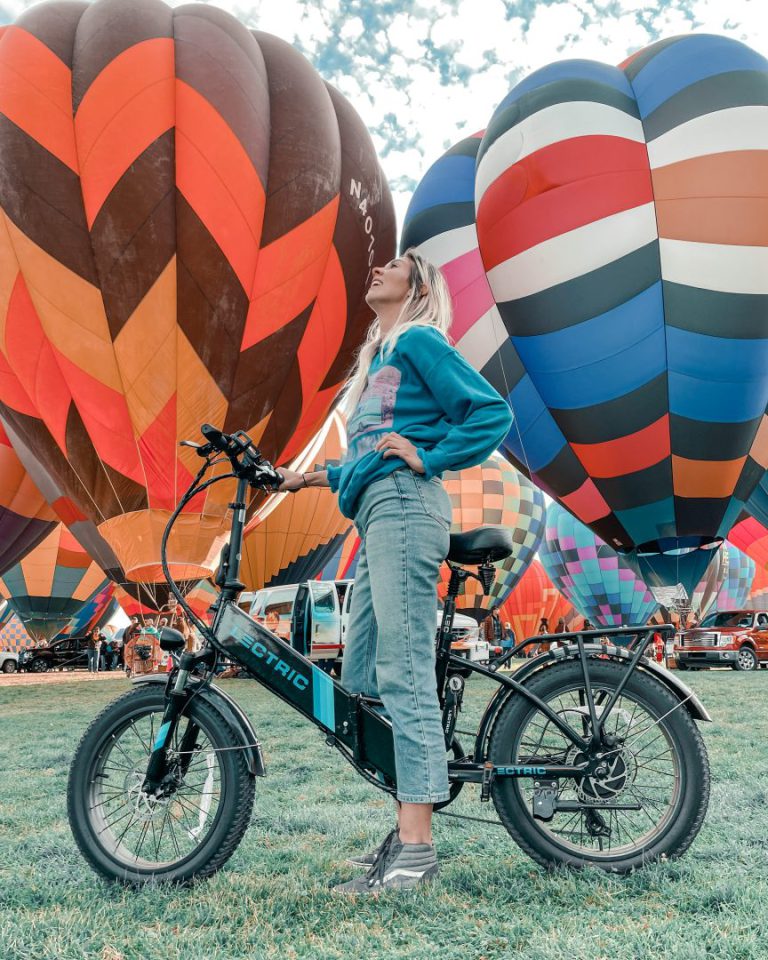 woman on a bike in front of hot air balloons