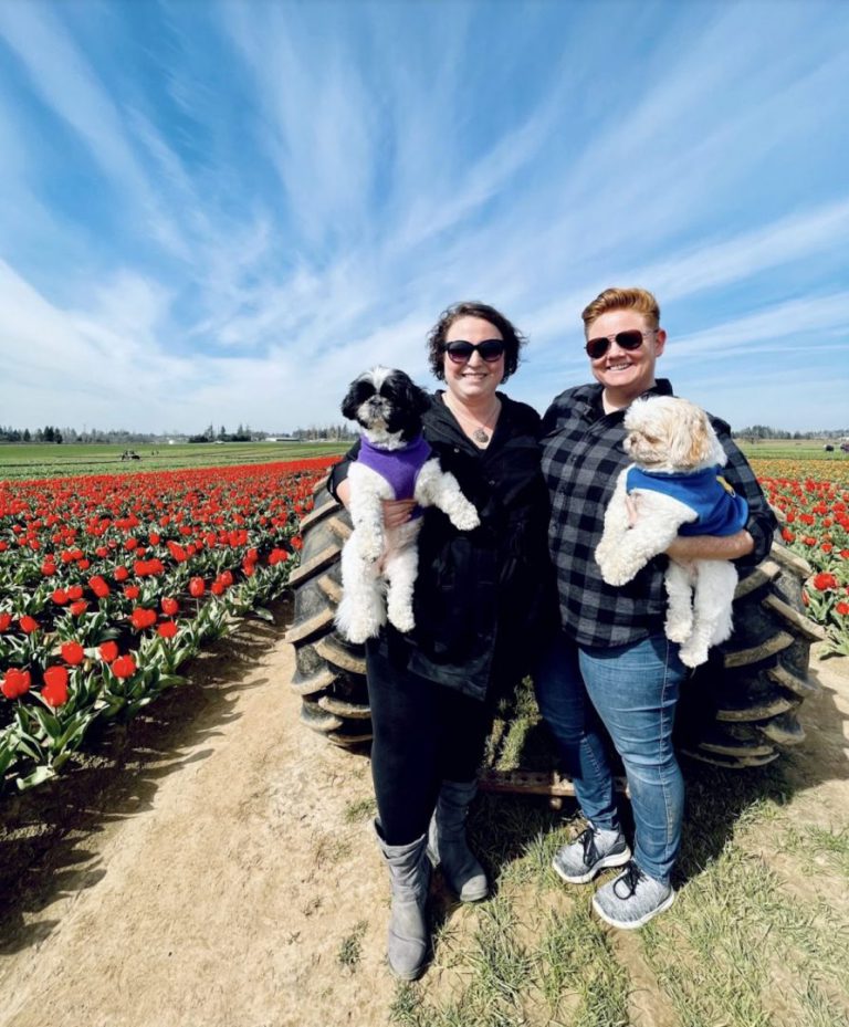 two women holding their dogs in a field of tulips