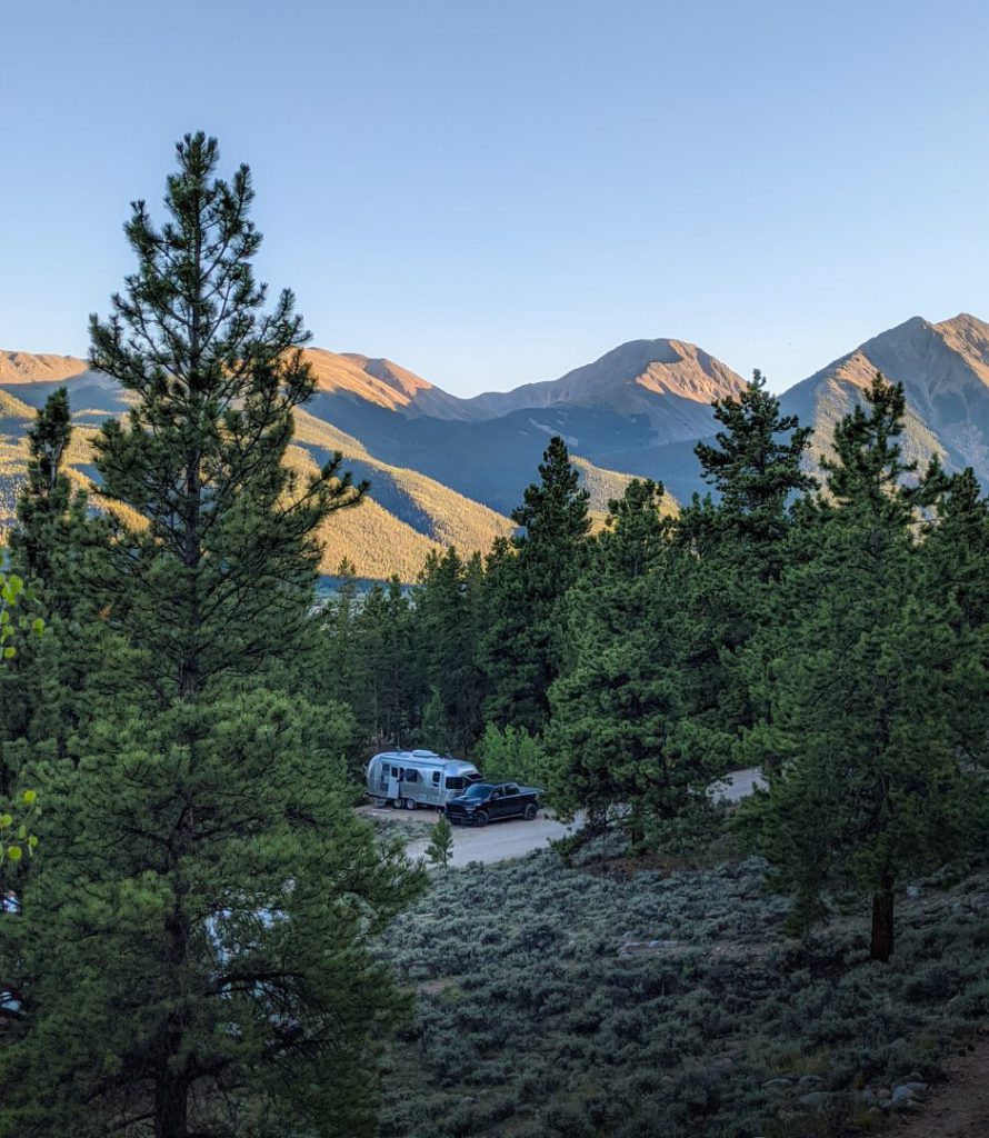 rv parked among trees and mountains