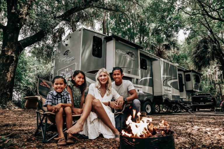 family sitting around a fire in front of an RV