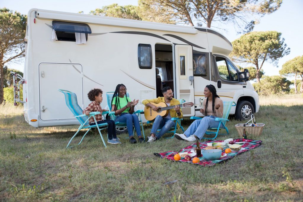 A family outside a camper playing guitar and singing