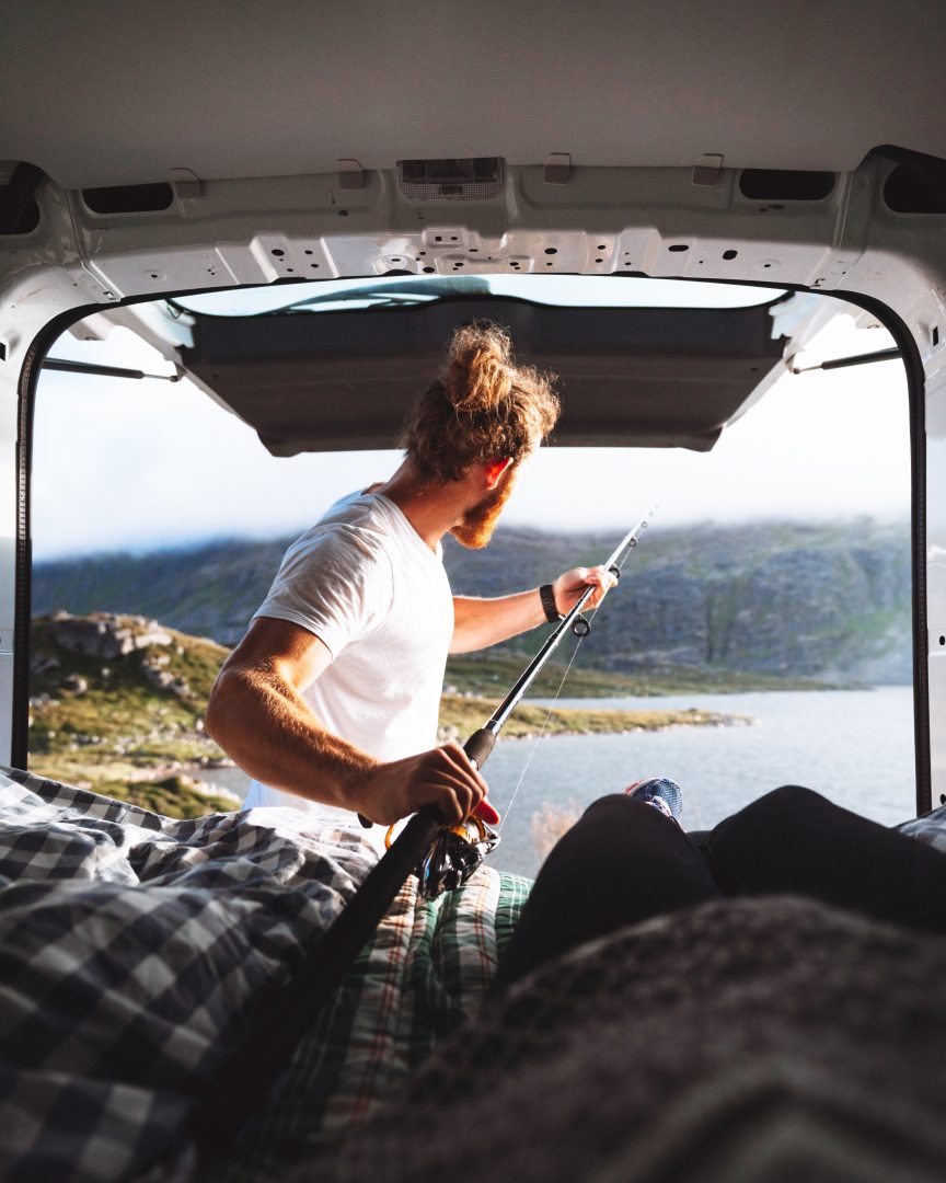 man in campervan with fishing pole