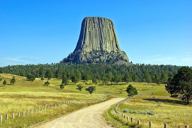 Devils Tower National Monument with blue sky and prairie surrounding it