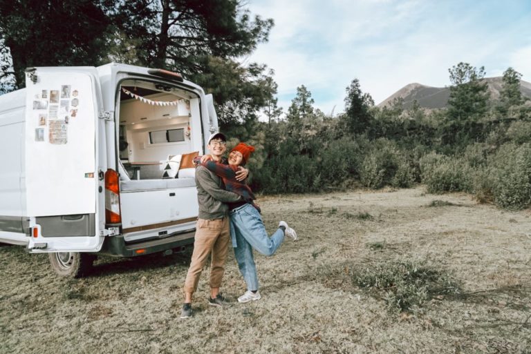Couple hugs while standing next to a camper van