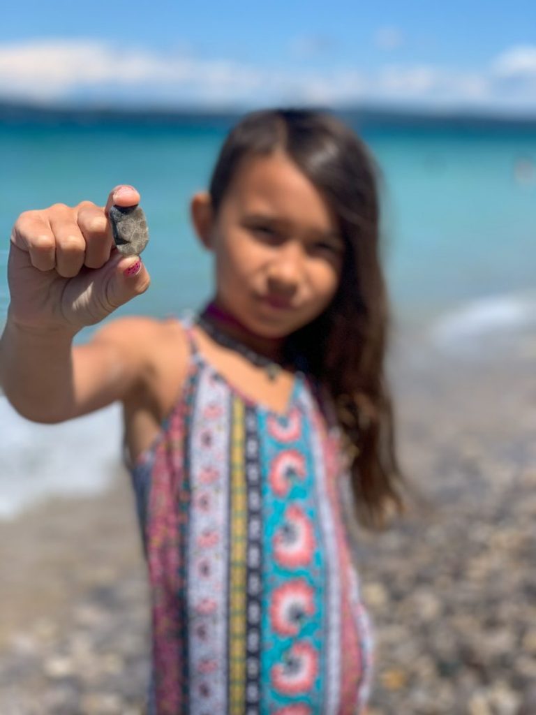 Young girl blurred, in focus she holds a small rock in front of her
