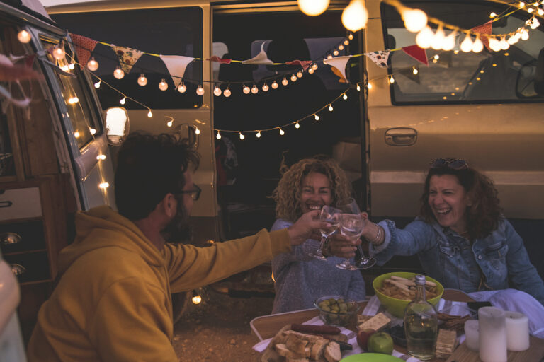 friends drinking wine outside a camper van