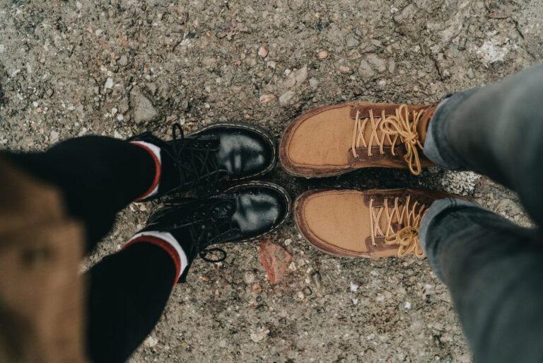 Looking down at a pair of black boots and brown boots