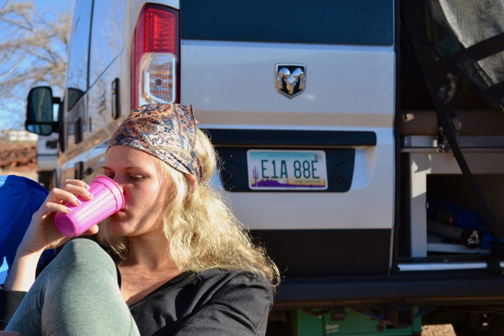 woman relaxes with a drink outside her campervan
