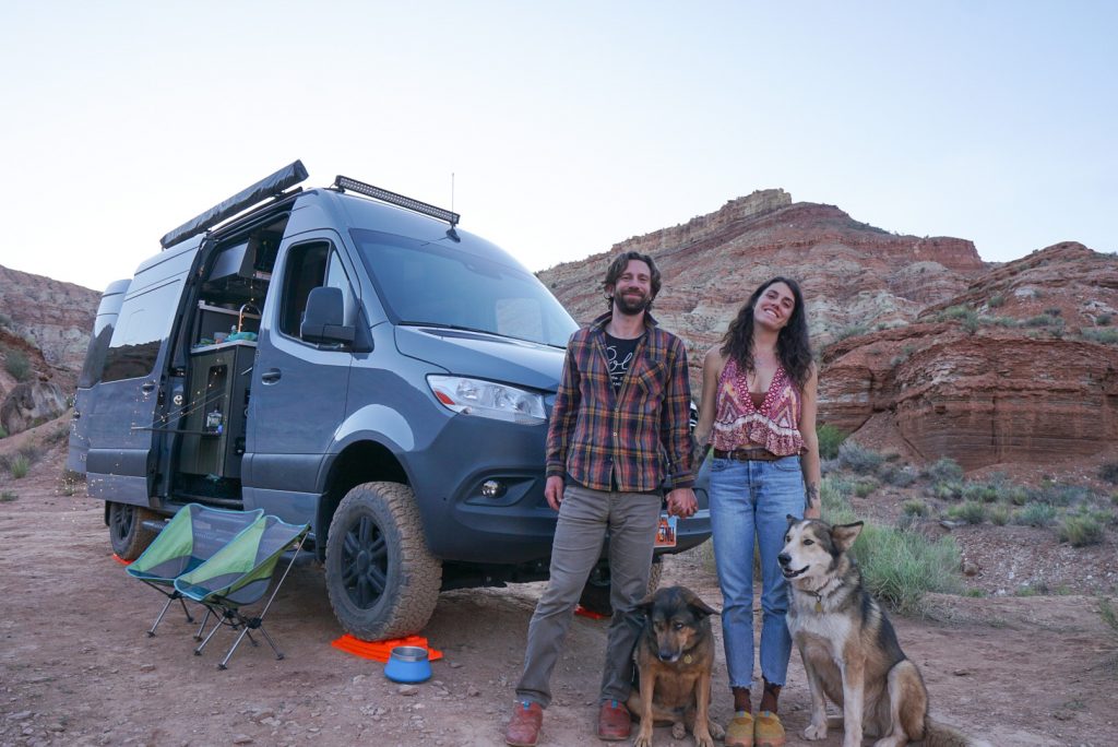 couple stands outside campervan with their two dogs