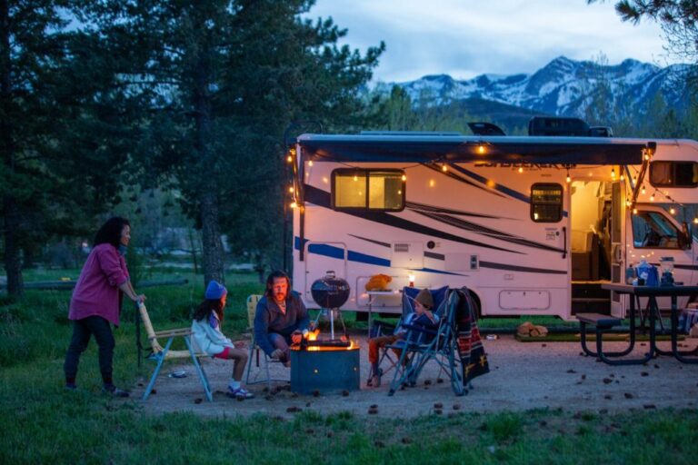 family relaxing outside a trailer at dusk