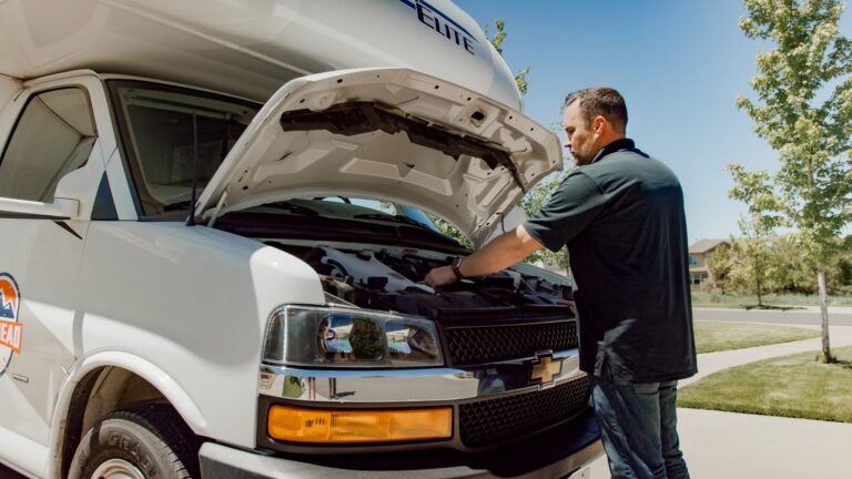 man working under the hood of an rv