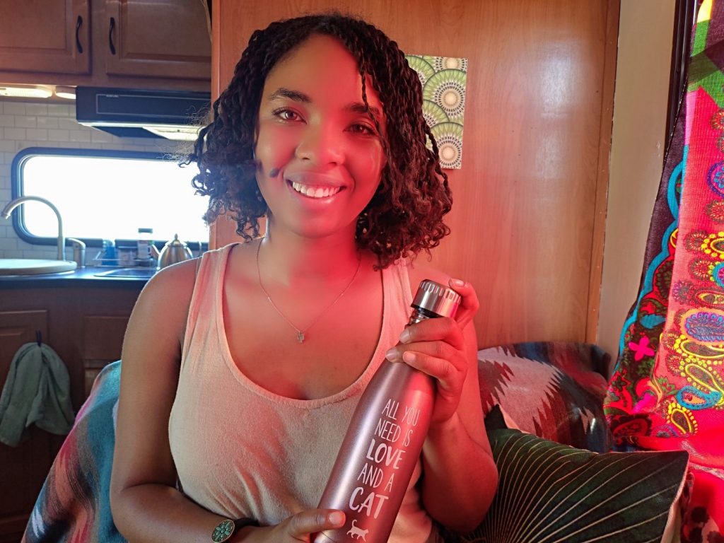 Young woman smiles and holds aluminum water bottle