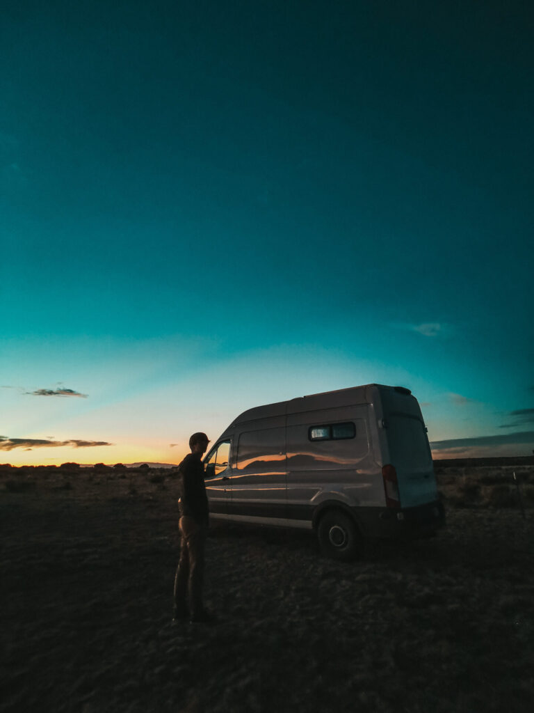 A man stand outside his camper van at night