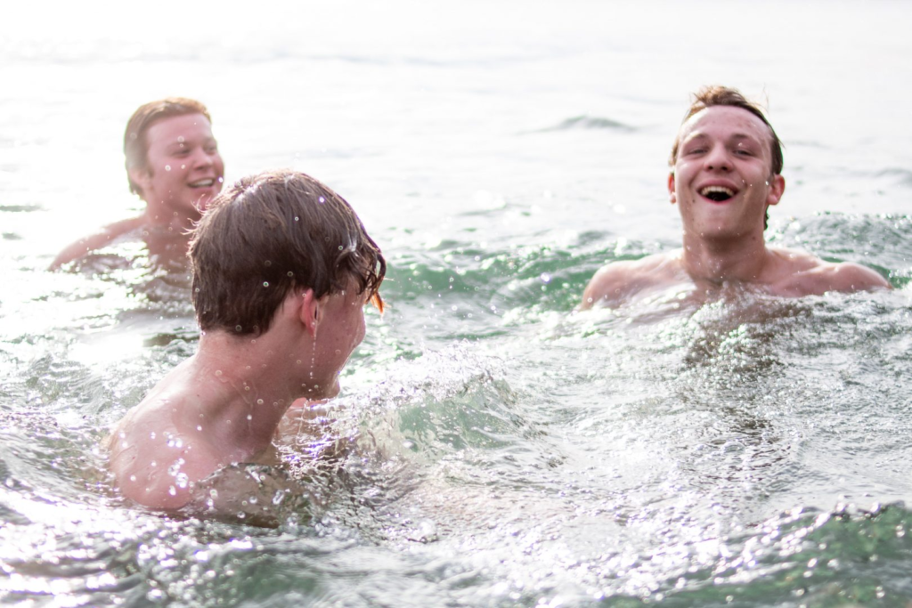 three guy swimming in a lake