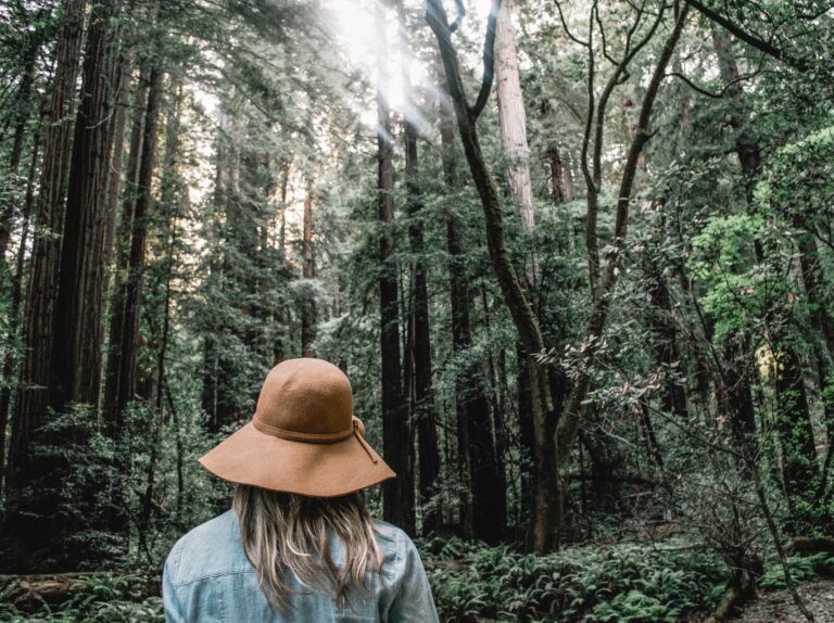 woman with hate standing in a forest