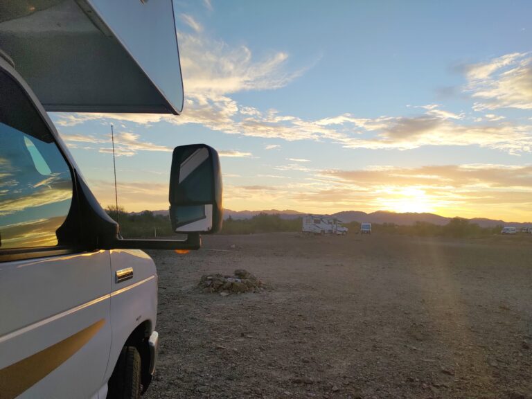 Class C RV parked in open area at sunrise