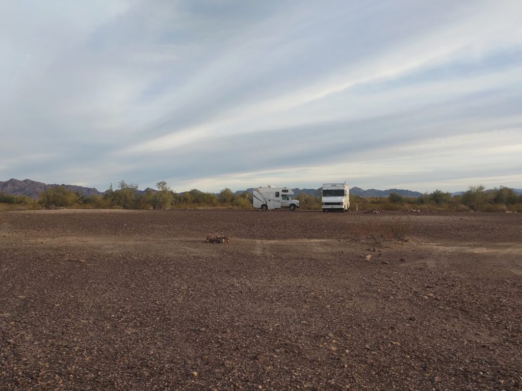 Open desert landscape with two Class C rvs parked next to each other on the horizon