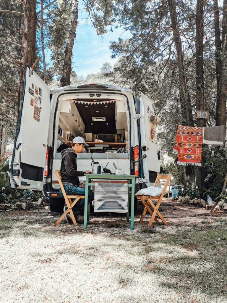 man sitting at a table next to his campervan