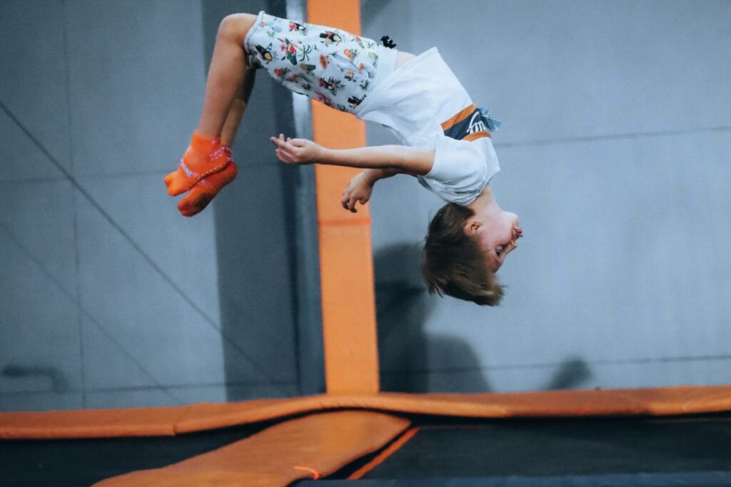 Young child does a back flip in an indoor trampoline park