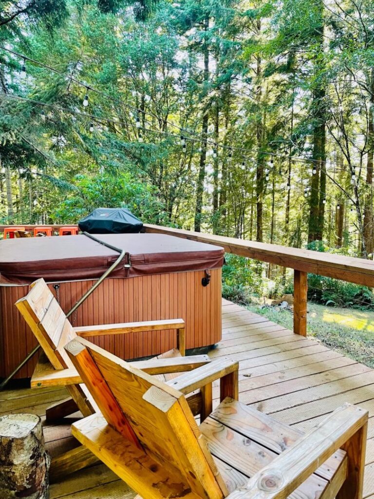 two chairs and a hot tub on the deck of a cabin in the woods