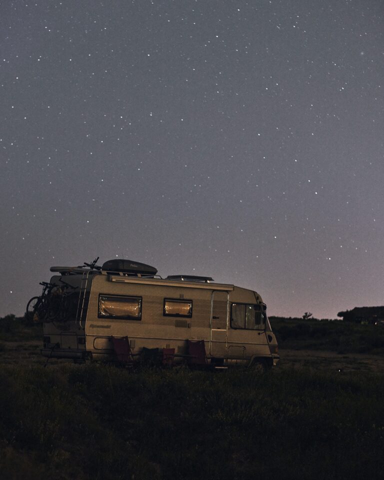 a camper parked at night with chairs set out front