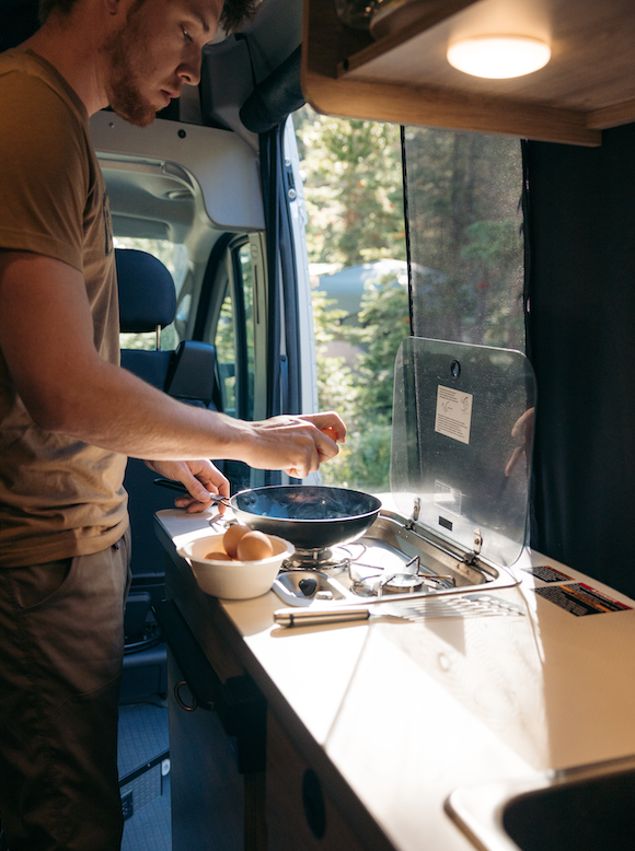 A man cracking eggs for breakfast in an RV kitchen