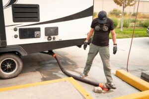 A man holding his RV sewer hose in place while it empties