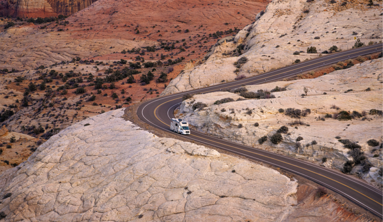 A far shot of an RV on a winding desert road