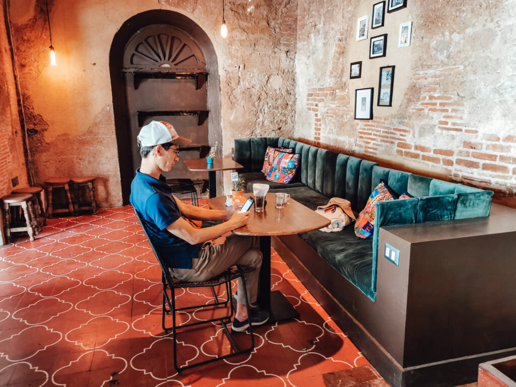 Man sits at the table of a cafe looking at his phone