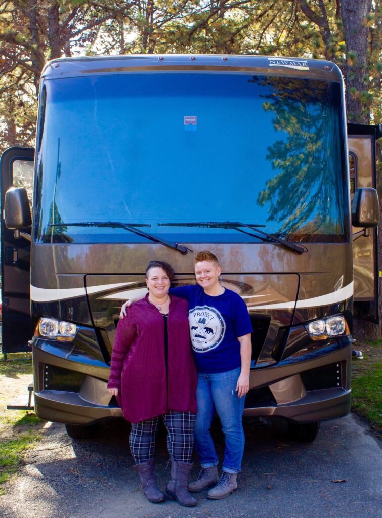 Couple stands in front of their class A RV