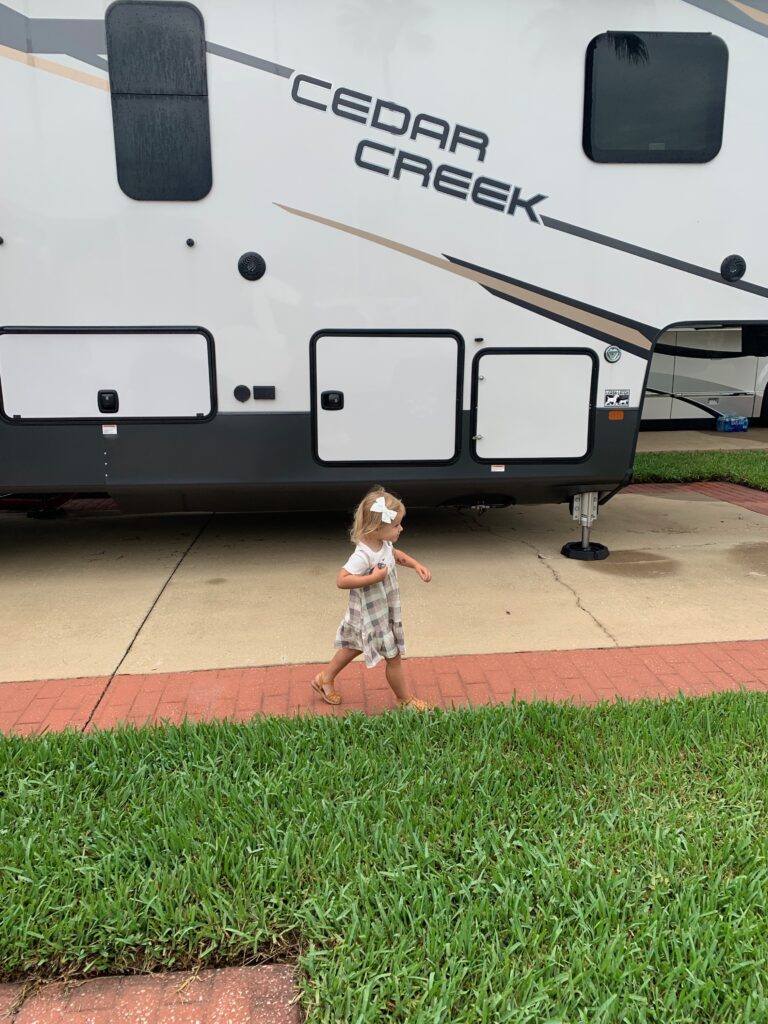 little girl running in front of an rv