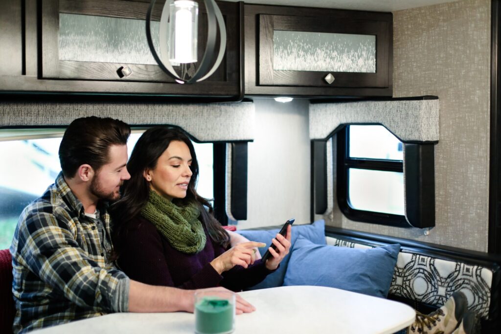 Man and woman sitting at RV dinette looking at phone together