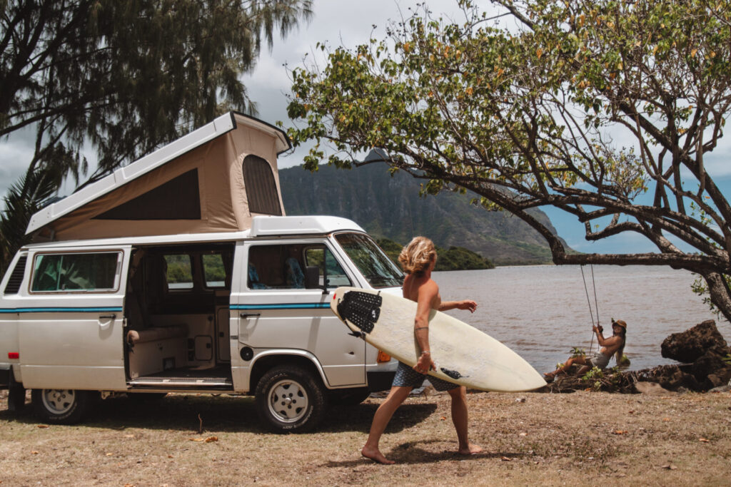 a surfer in a campervan by the beach