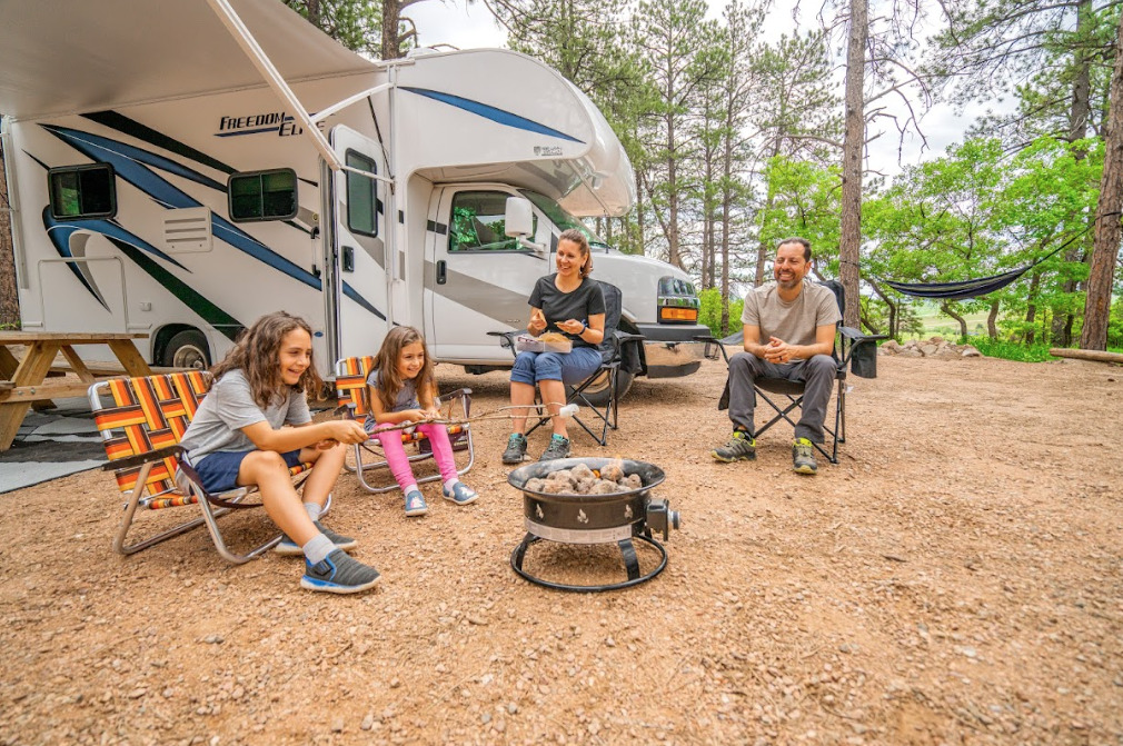 a family at a campfire in front of their Class C camper