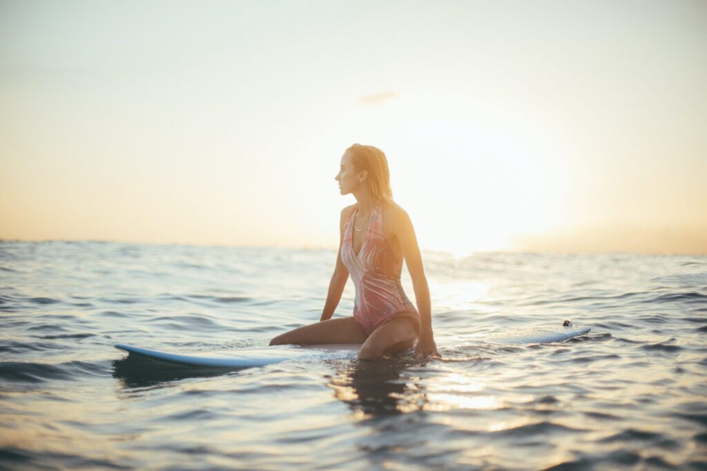 Woman sitting on surf board in water