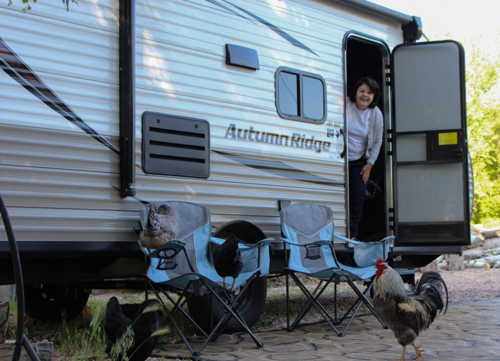 woman standing at RV door looking at chickens